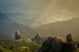 Paysage de montagne au lever du soleil avec une personne sur un sommet rocheux, symbole d’innovation responsable